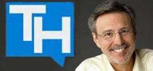 The image shows a smiling man with glasses and a light-colored shirt, positioned on the right side of the picture. To the left of him is a blue square with the white letters “TH” inside it. The “TH” represents the initials for Thom Hartmann, a well-known radio host, Thom Hartmann and his radio program