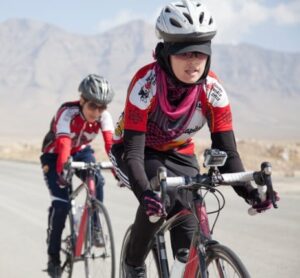 2 bicyclists on 10-speeds with silver helmets in red bike outfits