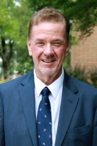 Man in a suit with trees in background