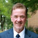 Man in a suit with trees in background