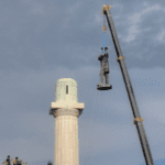 statue being taken off a pedestal with a crane