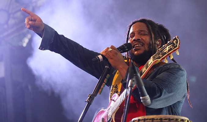 Stephen Marley holding a guitar and singing into a microphone