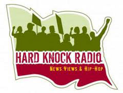 The image is a promotional graphic for "Hard Knock Radio". It consists of a background in the shape of a flag waving in the wind, with the upper half green in color with a silhouette of protesters with signs. The lower half is "Hard Knock Radio in red text on a white background over a solid red color for the last quarter of the flag. 