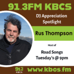 A poster for a DJ appreciation post from KBCS. This post features Rus Thompson, a white man with medium length grey hair, a short grey beard, and a black zip up jacket. He is outside with the sky behind him.