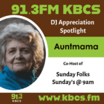 Graphic for a DJ Appreciation post in KBCS theme colors brown and chartreuse green. There is an image on the right of the graphic of Auntmama, a light skinned woman with grey hair looking at the camera with whimsy. She is wearing a blue cowl neck sweater and gold pearl earrings.