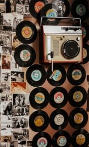 Old school portable turntable with handle hanging on wall with 7inch records attached to wall
