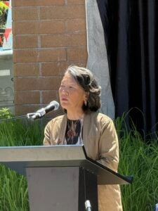 Mural artist Erin Shigaki speaks at the podium during mural dedication at Bellevue College.