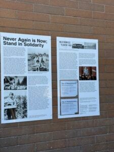 Never Again is Now mural plaque with text about artist Erin Shigaki's mural.