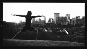 Black and white photo of person doing a yoga pose with urban background.