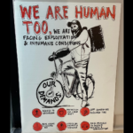 Photograph of a hand-drawn poster showing a delivery worker on a bicycle. Hand-drawn text reads "WE ARE HUMAN TOO, We are facing exploitation and inhumane conditions. Our demands: Access to bathroom, protection for e-bike theft, app companies disclose tips, real wages & hazard pay, limits on weight & distance, fair process to dispute ratings & termination."