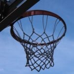 Underneath a basketball hoop with blue sky in the background.